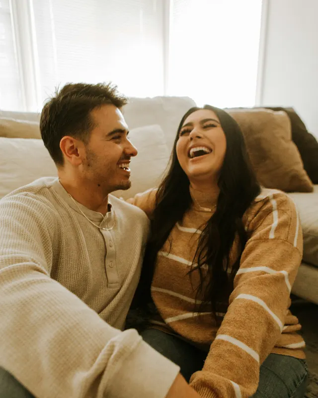Two people laughing together on the sofa