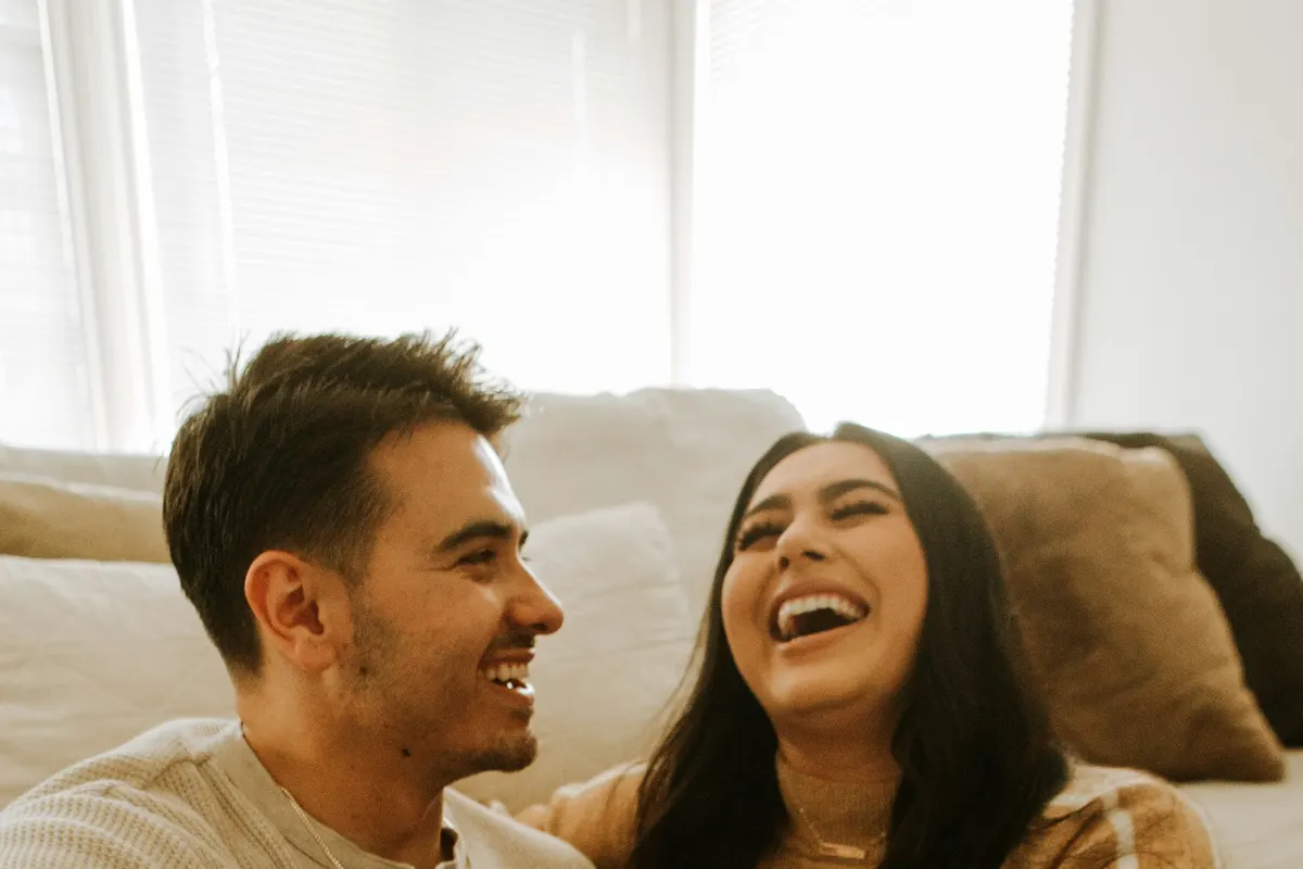 Two people laughing together on the sofa
