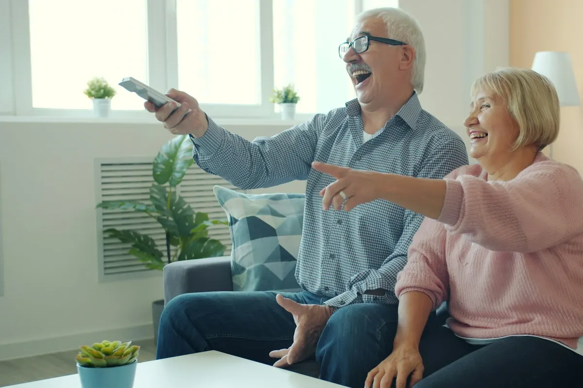Two people laughing and pointing at the TV